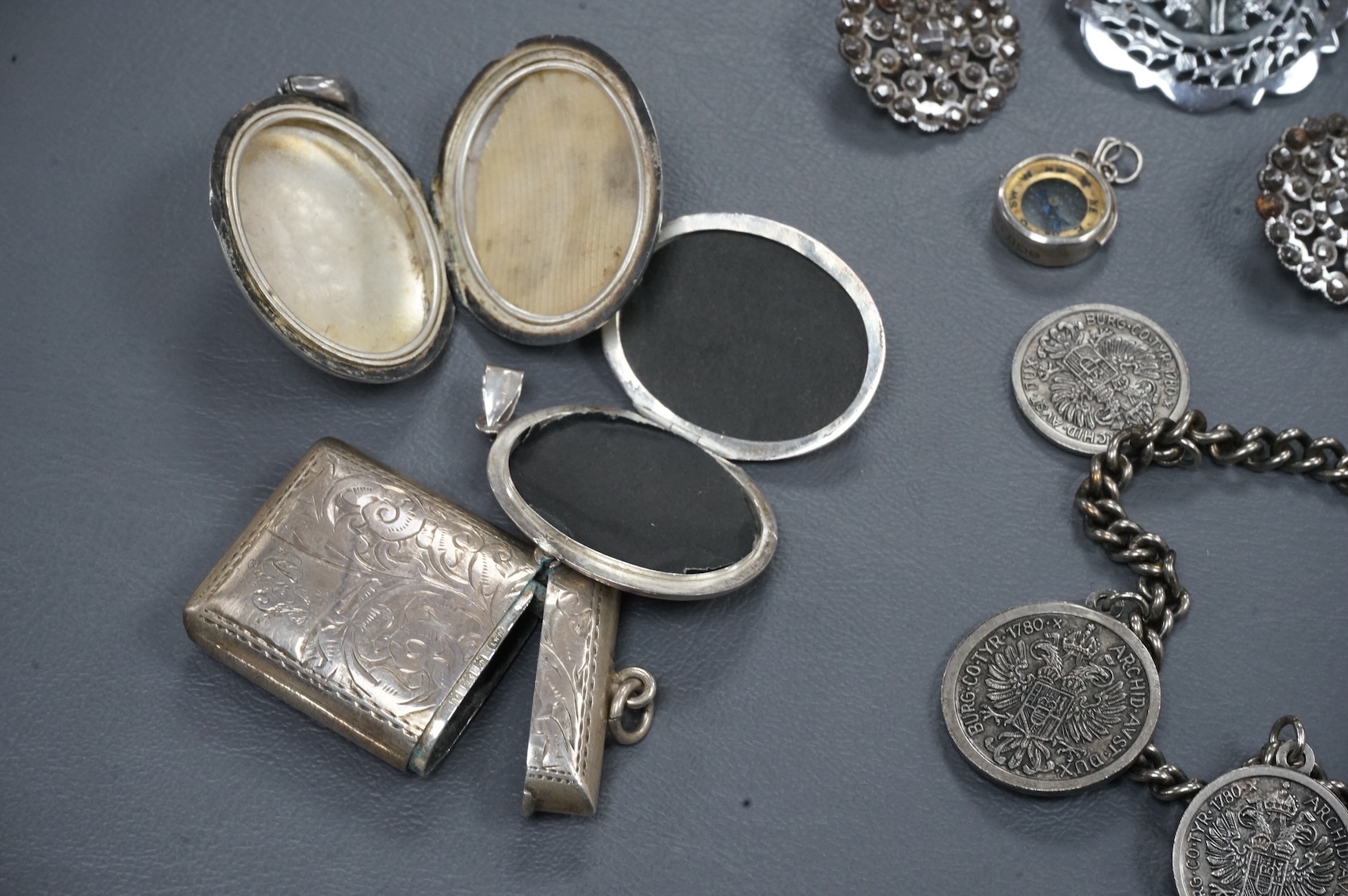 A mixed group of assorted collectables including a silver vesta case, two Victorian white metal lockets, two cut steel buttons, a coin bracelet and three other items.
